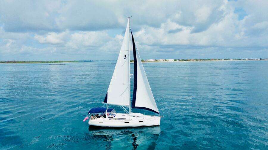Sailing yacht Beneteau Oceanis 45, 2015 model, cruising on calm blue waters under a cloudy sky.