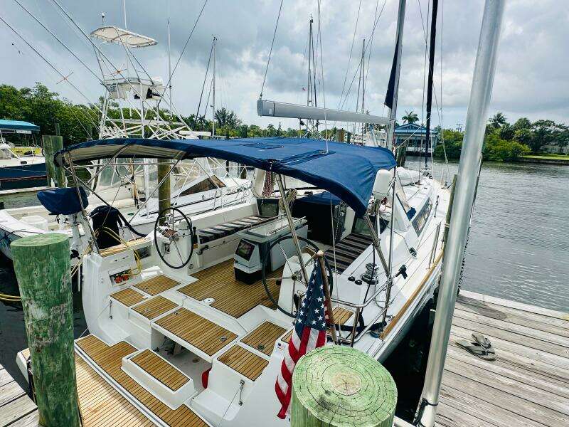 2015 Beneteau Oceanis 45 sailboat docked, featuring a blue canopy and wooden deck.