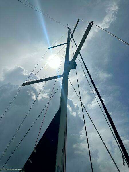 Mast of 2015 Beneteau Oceanis 45 sailboat against cloudy sky and sun.