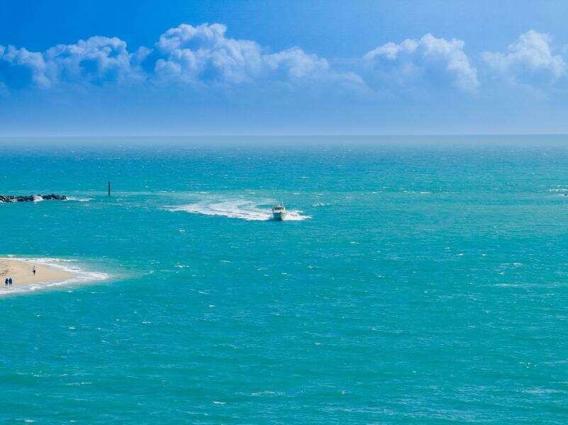 2007 Grady-White Express 360 boat cruising on turquoise ocean near sandy beach.
