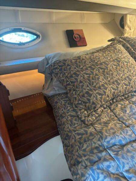 Cozy cabin interior of 2007 Monterey 350 Sport Yacht with patterned bedding and porthole window.