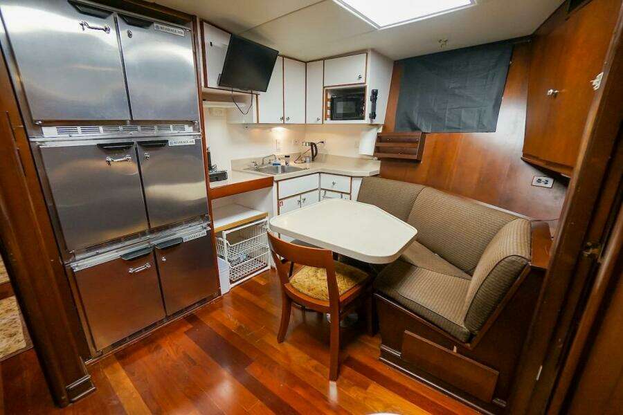 Cozy 1996 ABD 90 Explorer yacht kitchen with dining nook and stainless appliances.