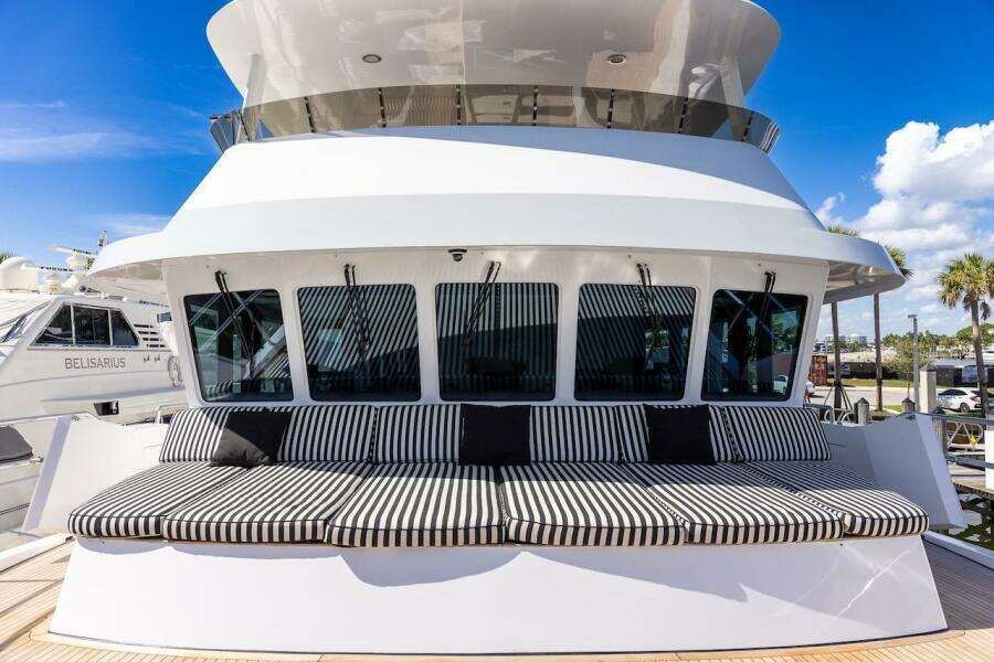 Luxury yacht ABD 90 Explorer 1996 with striped seating, docked under a clear blue sky.