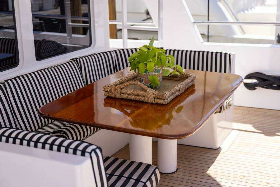 Luxury yacht interior with striped seating, wooden table, and decorative plant, ABD 90 Explorer 1996.