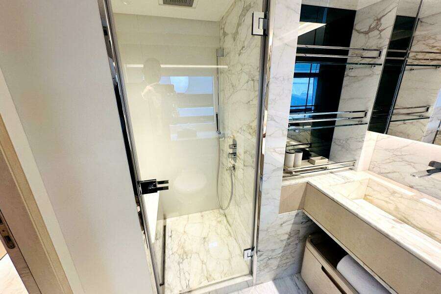 Luxurious marble bathroom in 2023 Majesty 120 yacht, featuring glass shower and modern fixtures.