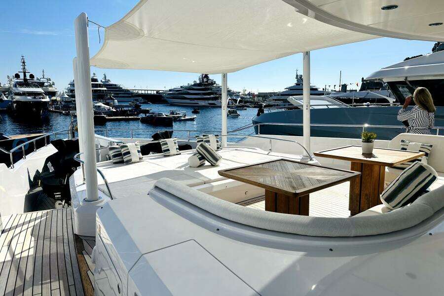 Luxurious 2023 Majesty 120 yacht deck with elegant seating, overlooking marina filled with yachts.
