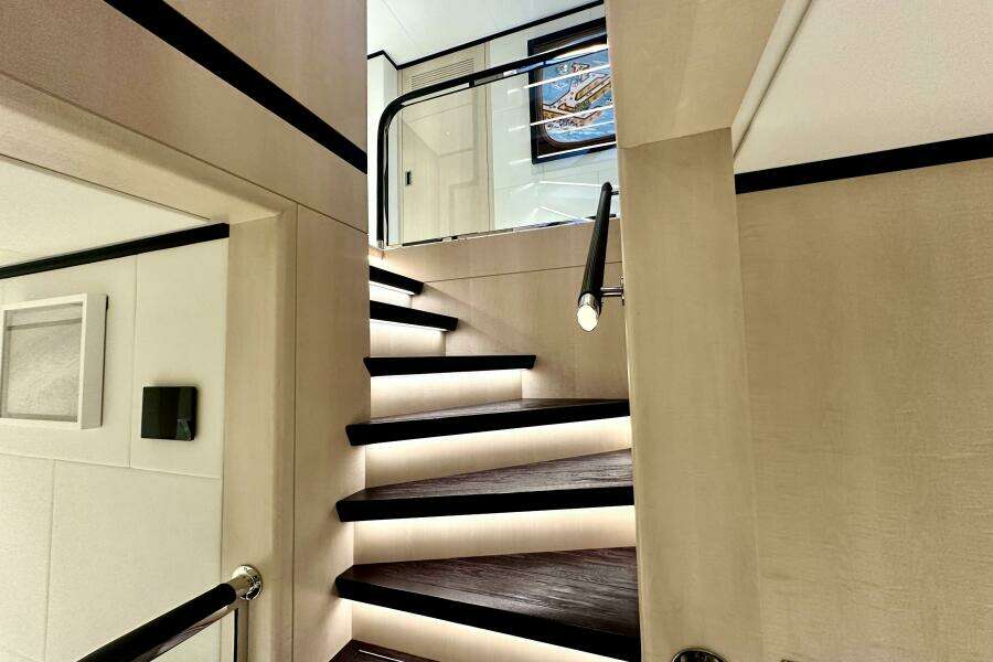 Luxurious interior staircase of 2023 Majesty 120 yacht with modern lighting.