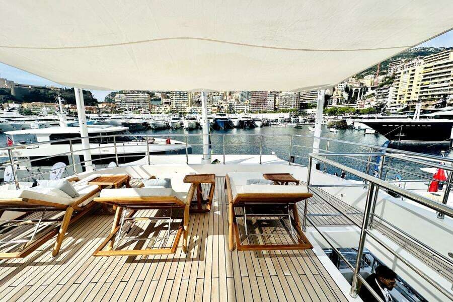 Luxurious 2023 Majesty 120 yacht deck with sun loungers, overlooking a marina.