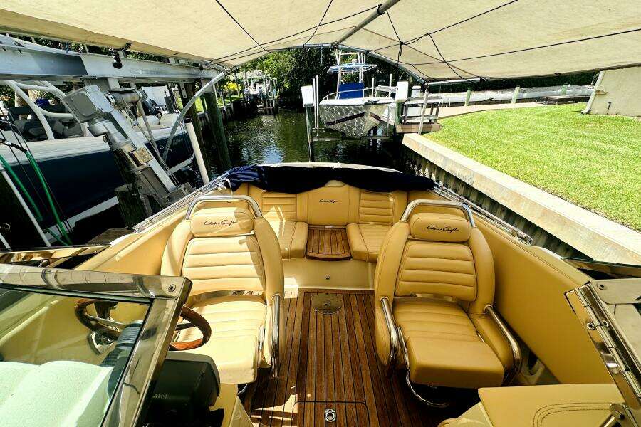 2013 Chris-Craft Corsair 22 boat with tan leather seats and wooden deck under canopy.