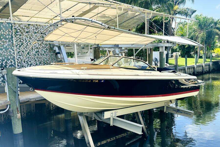 2013 Chris-Craft Corsair 22 boat on lift, docked near lush greenery.