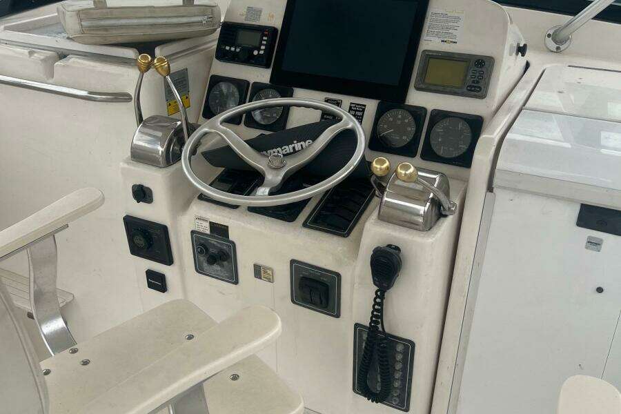 Control panel of a 2001 Pursuit 3000 Offshore boat with steering wheel and gauges.