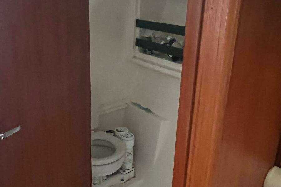 2001 Pursuit 3000 Offshore boat bathroom with wooden door and compact toilet.