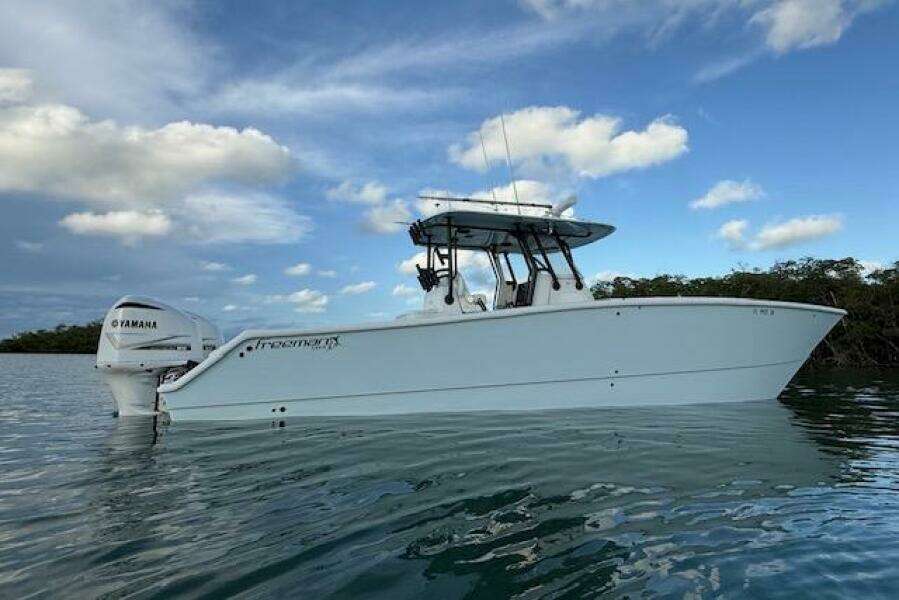 2019 Freeman 34 boat on calm water with Yamaha engine, under a partly cloudy sky.