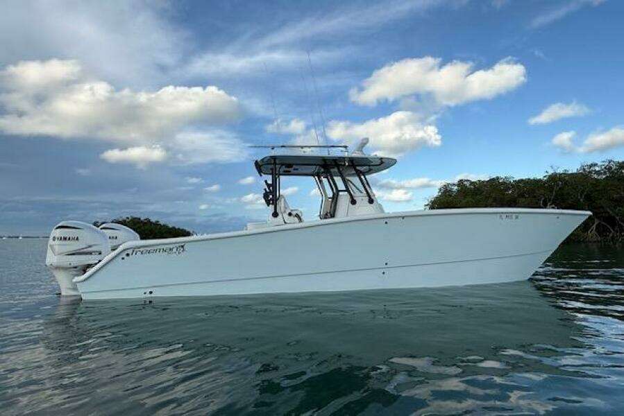2019 Freeman 34 boat with Yamaha engines on calm water under a blue sky.