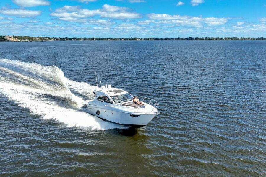 2014 Beneteau Gran Turismo 44 yacht cruising on open water under a clear blue sky.