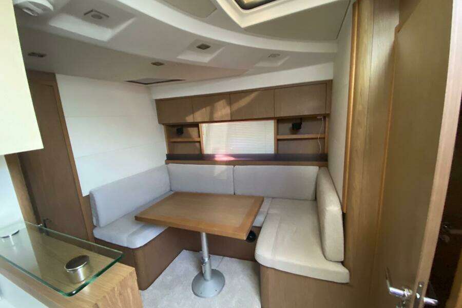 2014 Beneteau Gran Turismo 44 interior with cozy dining area and wooden cabinetry.