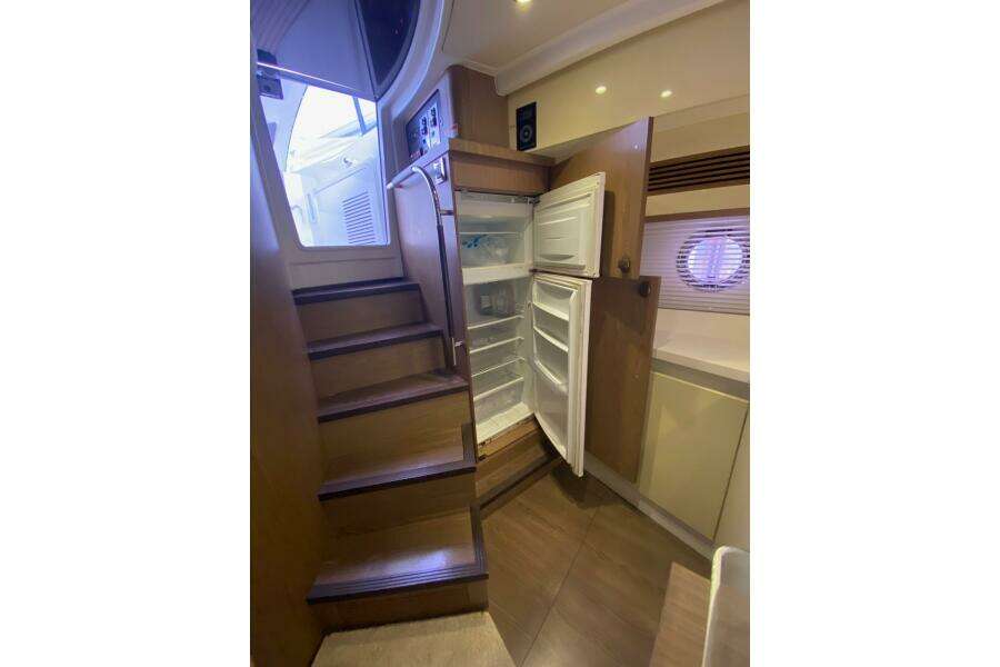 Interior of 2014 Beneteau Gran Turismo 44 yacht with open refrigerator and wooden stairs.