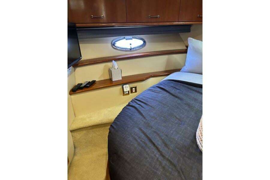Interior of 2004 Carver 466 Motor Yacht bedroom with porthole, bed, and storage cabinets.