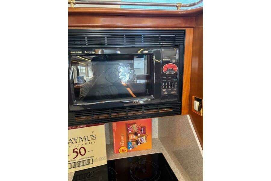 Microwave in 2004 Carver 466 Motor Yacht kitchen with snacks and wine box nearby.