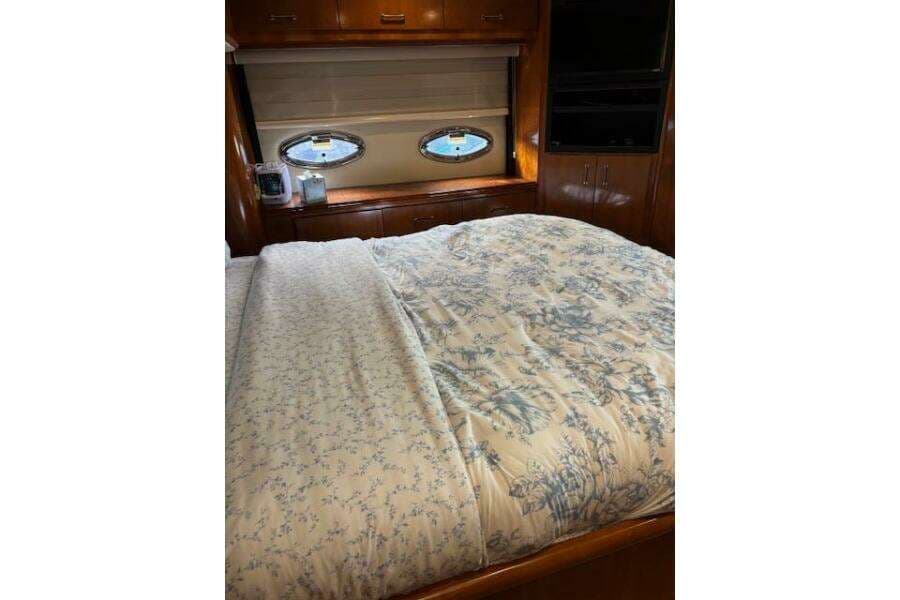 Luxurious bedroom interior of 2004 Carver 466 Motor Yacht with floral bedding and porthole windows.