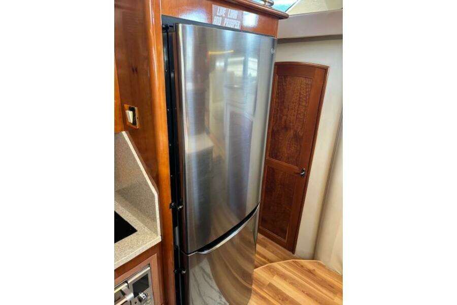 Stainless steel refrigerator in 2004 Carver 466 Motor Yacht interior, featuring wood accents.