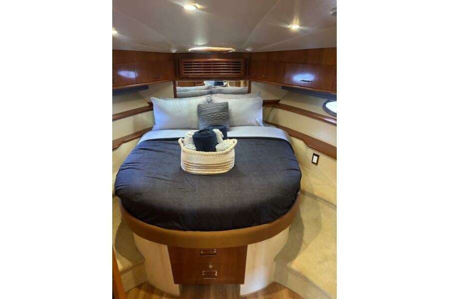 Luxurious bedroom interior of 2004 Carver 466 Motor Yacht with elegant bedding and wood accents.