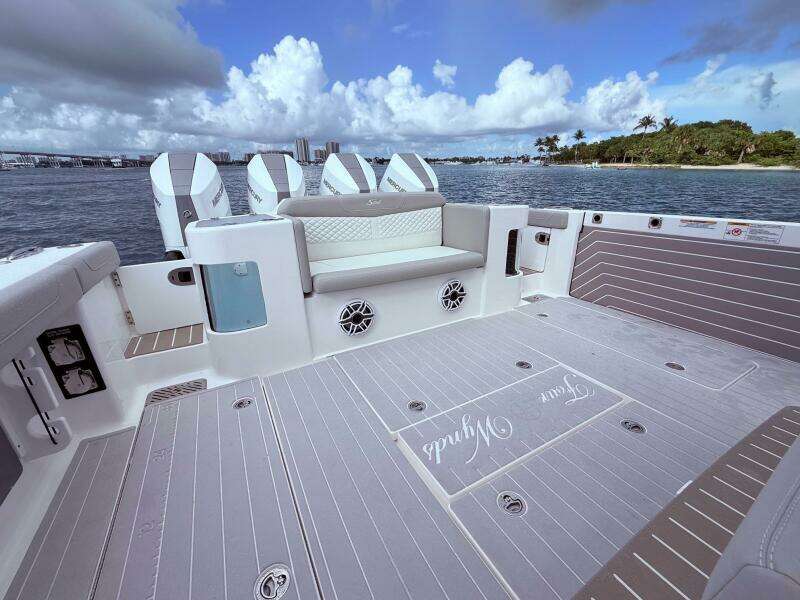 2024 Scout 400 LXF boat deck with seating, ocean view, and four outboard engines.