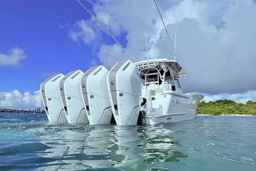 2024 Scout 400 LXF boat with multiple engines on water, under a clear blue sky.