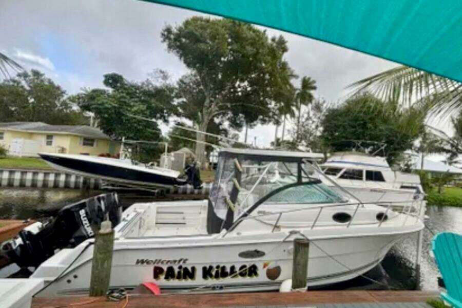 2002 Wellcraft 290 Coastal boat named "Pain Killer" docked by a canal.